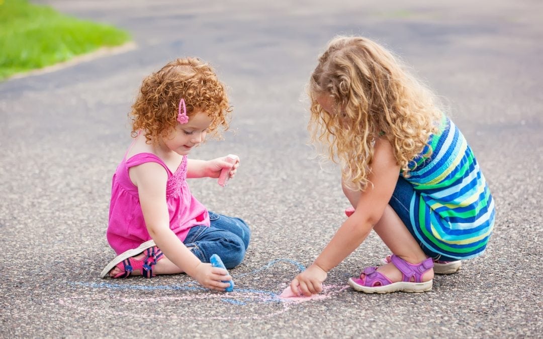 Girls drawing on a concrete driveway with chalk. Concrete Leveling: Top 6 Texas Homeowner Questions Answered